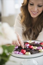Woman choosing chocolate from cake stand.
Photo : Jamie Grill