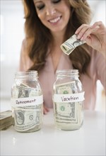 Woman putting money in jar.
Photo : Jamie Grill