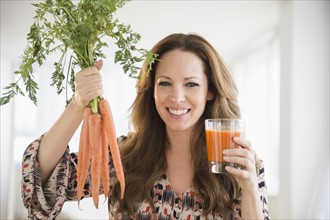 Portrait of woman holding carrots and carrot juice.
Photo : Jamie Grill