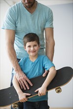 Father and son (8-9) holding skateboard .
Photo : Jamie Grill
