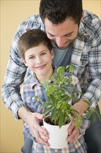 Father and son (8-9) holding potted plant .
Photo : Jamie Grill