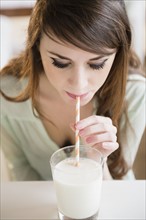 Young woman drinking milk with straw.
Photo : Jamie Grill