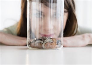 Young woman looking at coins in jar.
Photo : Jamie Grill