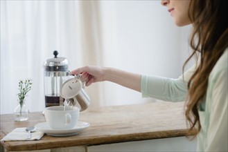 Young woman pouring milk into coffee cup.
Photo : Jamie Grill