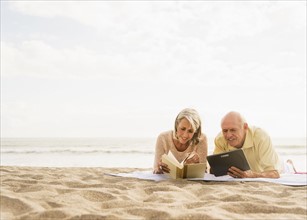 Senior couple reading books on beach.
Photo : Daniel Grill
