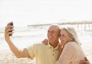 Senior couple taking picture of themselves on beach.
Photo : Daniel Grill