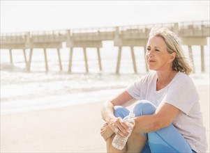 Senior woman sitting on beach.
Photo : Daniel Grill