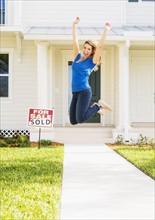 Woman jumping in front of new house.
Photo : Daniel Grill