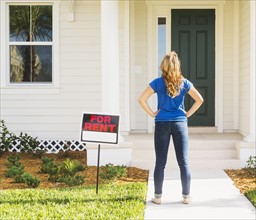 Rear view of woman standing next to for rent sign.
Photo : Daniel Grill