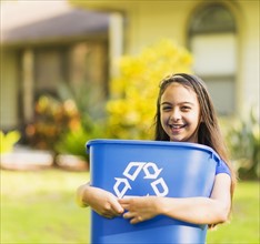 Portrait of girl ( 8-9) holding recycling bin.
Photo : Daniel Grill