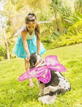 girl (8-9) wearing fairy costume playing with dog.
Photo : Daniel Grill