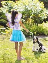 girl (8-9) wearing fairy costume playing with dog.
Photo : Daniel Grill
