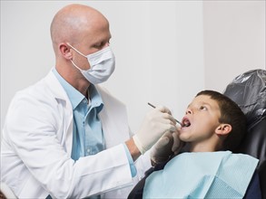 Dentist checking mouth of patient( 12-13).