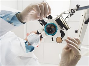 Lowe angle view of dentist using microscope.