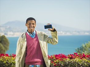 Portrait of smiling man holding smartphone.