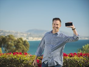 Portrait of smiling man holding smartphone.