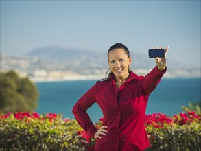 Portrait of smiling woman holding smartphone.