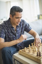 Man playing chess in living room.