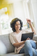 Woman using digital tablet on sofa.