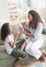 Daughter (8-9) and mother playing clapping game .