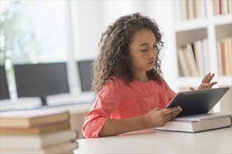 Girl (8-9) using digital tablet in classroom.