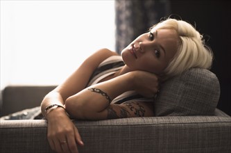 Portrait of blonde woman relaxing on sofa.