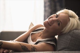 Portrait of blonde woman relaxing on sofa.