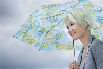 Blonde woman under umbrella.