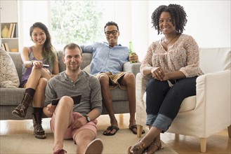 Portrait of group of friends sitting in living room.