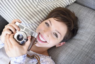 Portrait of young woman holding old fashioned camera.
