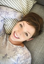 Portrait of smiling woman lying on sofa.