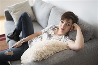 Portrait of smiling woman sitting on sofa.
