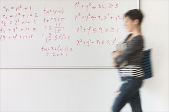Young woman walking in front of whiteboard.