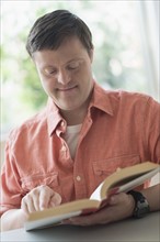 Man with down syndrome reading book.