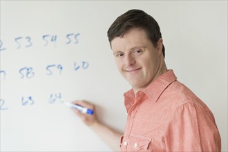 Man with down syndrome writing on whiteboard.