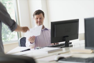 Man with down syndrome working in office.
