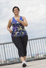 Woman jogging on bridge.