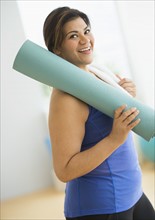 Woman holding exercise mat at gym.