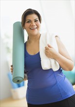 Woman holding exercise mat at gym.