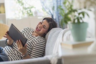 Portrait of happy woman lying on sofa with tablet pc.