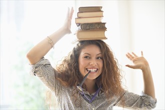Portrait of woman with books on top of head.