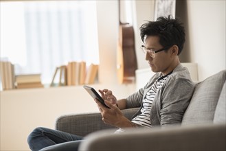 Man sitting on sofa and using tablet.