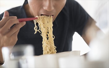 Man eating noodles with chopsticks.