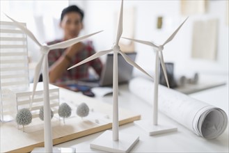 architect in background, Wind turbine models on desk.