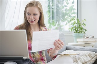 Young woman paying bills at home