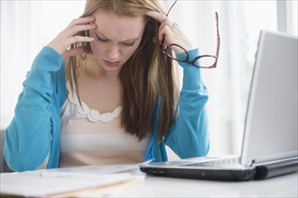 Frustrated young woman looking at bills