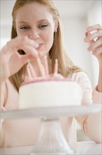 Woman putting candles on birthday cake