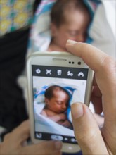 Mother photographing newborn daughter
