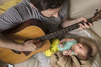 Father playing guitar for newborn daughter