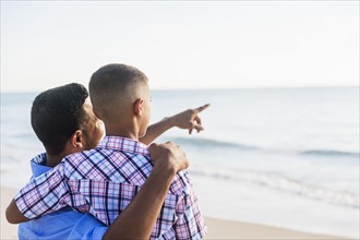 Father and son (10-11) embracing on beach